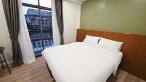 a bedroom with a large white bed and a window at SUP Hometel Phuket in Ban Thalat Choeng Thale