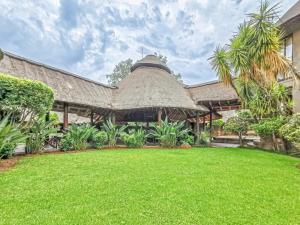 a large house with a grass roof and a yard at Cherry Creek at Zebula in Warmbaths