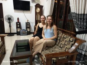 two women sitting on a couch in a room with a clock at Kandyan Rest in Talakolawela