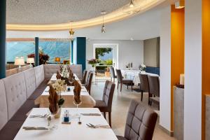 un ristorante con tavoli e sedie bianchi e finestre di Hotel Paradies a Tirolo
