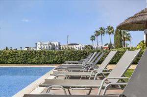 a row of chaise lounge chairs next to a swimming pool at Aquamar Pro 402 in Quarteira