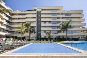 a hotel with a swimming pool and chairs and a building at Aquamar Pro 402 in Quarteira