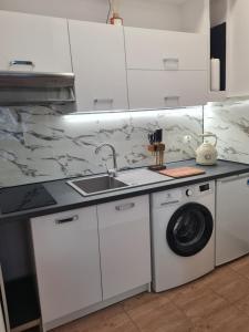 a white kitchen with a sink and a washing machine at Zakątek Spokoju in Toruń +20 photos