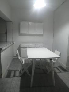 a white kitchen with a table and two chairs at Punta hermosa casa playa in Punta Hermosa