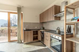a kitchen with wooden cabinets and a large window at Nest Family, Bedollo Ospitar in Bedollo