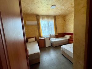 a small room with two beds and a window at Димоли in Elin Pelin