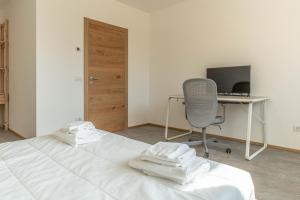 a bedroom with a bed with a desk and a chair at Nest Family, Bedollo Ospitar in Bedollo