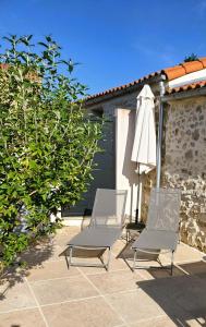 two chairs and an umbrella on a patio at Gîtes Arvor et Tevenn in Saint-Brevin-les-Pins