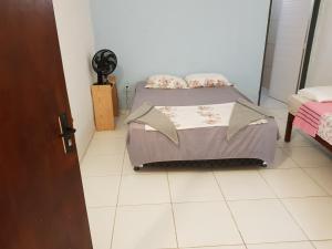 a small bedroom with two beds and a fan at Casa Dos Vovôs Pousada em Canoa Quebrada in Aracati