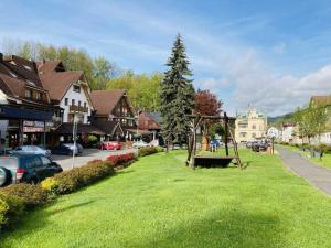 a park with a bench in the grass in a town at Apartmán Denisa in Rokytnice nad Jizerou