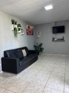 a living room with a black couch and a tv at A queridinha do Orange in Itamaracá