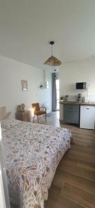 a bedroom with a bed and a kitchen and a table at Studio85 in La Gaubretière