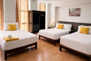 two beds with yellow pillows in a room at Hotel Kuwasi in Chiclayo