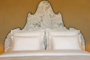 a bed with a white headboard and two pillows at Josefina unique hotel, adult only in Kozina
