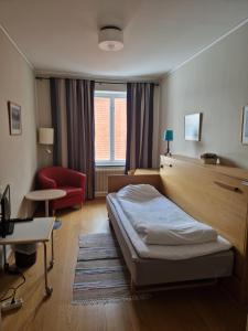 a bedroom with a bed and a red chair at Dorotea Logi B&B in Dorotea