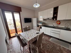 a kitchen with a table with chairs and a kitchen with white cabinets at MR1 House Gallipoli in Gallipoli