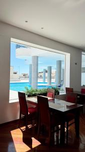 a dining room with a table and chairs and a large window at The Navigator - Ocean Heights & Residences in Olhos de Água