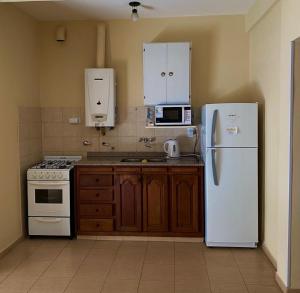 a kitchen with a white refrigerator and a stove at OLÍMPICO in Concepción del Uruguay