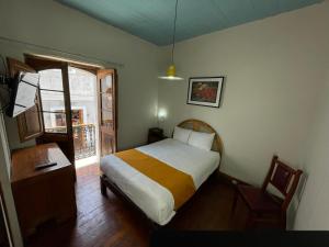 a bedroom with a bed and a table and a window at Hostal Lluvia de Oro in Arequipa