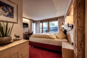 アローザにあるAlpinArosaのベッドと窓が備わるホテルルーム