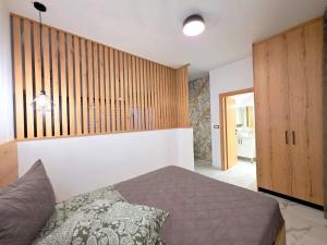 a bedroom with a bed and a wooden wall at Anthouli Homes 1, steps from beach and centre in Kardamaina