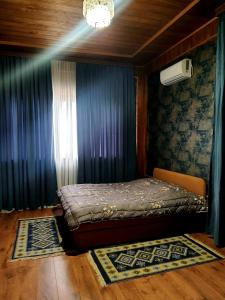 a small bed in a room with blue curtains at Brick House Melodies in Tsqaltubo