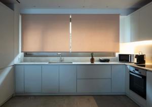 a kitchen with white cabinets and a sink and a microwave at Fenia's Paradise Villa in Houlakia