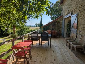 a wooden deck with tables and chairs and a building at Bus magique avec tente glamping in Saint-Palais