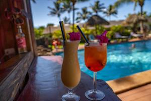 two cocktails sitting on a table next to a swimming pool at Taha Tai in Hanga Roa