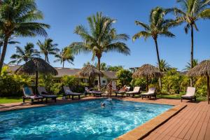 a swimming pool with chairs and palm trees at Taha Tai in Hanga Roa