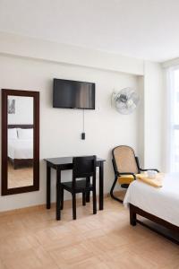 a bedroom with a desk and a chair and a mirror at Hotel Kuwasi in Chiclayo