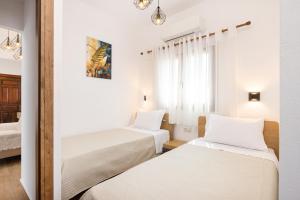 two beds in a room with white walls at Azzure Studio in Kokkari