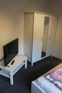 a hotel room with a television and a bed at Bismarck Hostel Öhringen in Öhringen