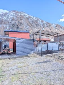 a building with a picnic table in front of a mountain at Nikolozi in Kazbegi