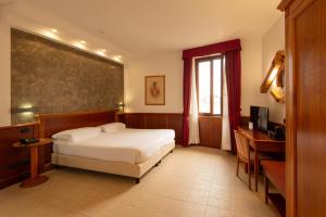 a bedroom with a bed and a desk and a window at Hotel Duomo - Etruria Collection in Orvieto +27 photos