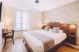 a bedroom with a large bed and a desk at Hôtel de la Poste in Chablis