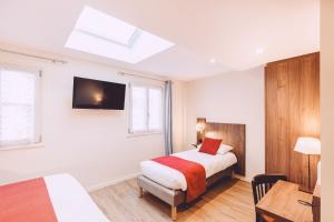 a bedroom with a bed and a television on the wall at Hôtel de la Poste in Chablis