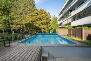 a swimming pool with a wooden deck next to a building at FoBala Apartman in Balatonföldvár