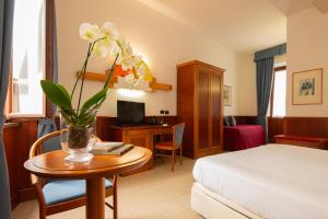 a hotel room with a bed and a vase with flowers on a table at Hotel Duomo - Etruria Collection in Orvieto