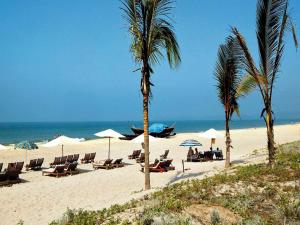 uma praia com cadeiras e palmeiras e o oceano em The Byke Old Anchor Beach Resort & Spa em Cavelossim