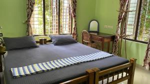 a bedroom with a bed and a desk and windows at SEVENSTAR RESIDENCY in Varkala