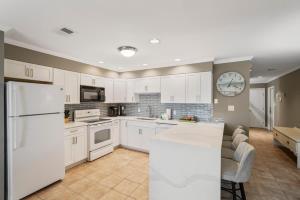 a kitchen with white cabinets and a clock on the wall at Blue Tide #8A in Seacrest