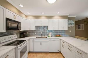 a kitchen with white cabinets and white appliances at Blue Tide #8A in Seacrest