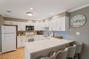 a kitchen with white cabinets and a large clock on the wall at Blue Tide #8A in Seacrest +20 photos