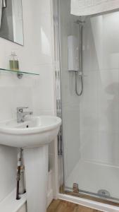 a white bathroom with a sink and a shower at Trelawney Guest House Room only in Falmouth