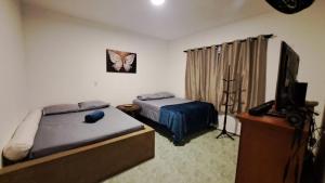 a bedroom with two beds and a flat screen tv at Sitio Serra e Mar in Saquarema +6 photos