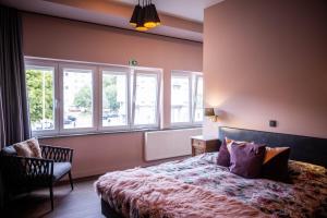 a bedroom with a bed and a chair and windows at Nova Zembla in Mechelen
