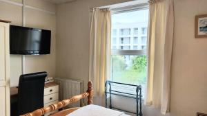 a bedroom with a bed and a window with a television at Trelawney Guest House Room only in Falmouth