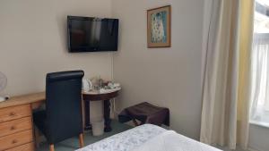 a bedroom with a bed and a desk and a tv on the wall at Trelawney Guest House Room only in Falmouth +19 photos