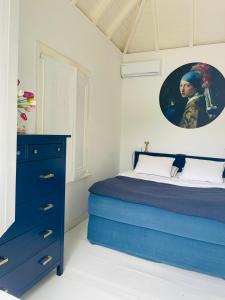 a bedroom with a blue bed and a painting on the wall at Dushi Blou, private monumentje in Otrabanda in Willemstad